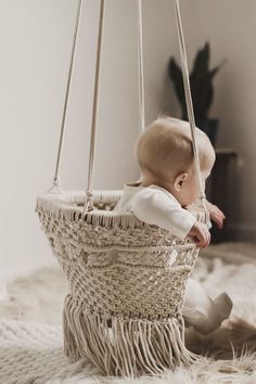 a baby is sitting in a hanging basket