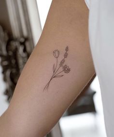 a woman's arm with a small flower tattoo on the left side of her arm