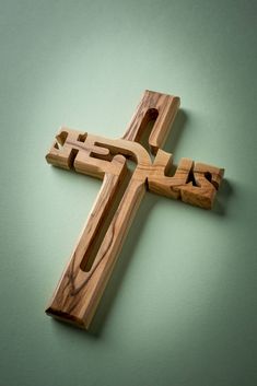 a wooden cross with the word jesus carved into it on a green tablecloth background