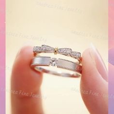 a woman's hand holding a wedding ring with two diamonds on the side and an arrow in the middle