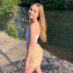 a woman standing on the edge of a cliff next to a river