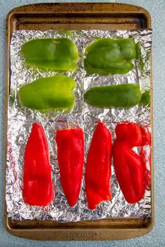 red peppers and green peppers sitting on tin foil in a baking pan, ready to go into the oven