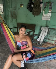 a woman sitting in a hammock with her legs crossed and looking at the camera