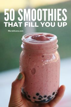 a hand holding a pink smoothie in a mason jar with the words 50 smoothies that fill you up