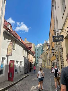 people are walking down an alley way in the old part of town on a sunny day