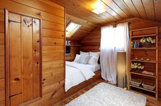 a bedroom with wood paneling and white bedding in an attic style room,