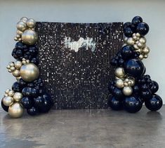 black and gold balloons in front of a mosaic wall