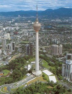 an aerial view of a tall tower in the middle of a city with mountains in the background