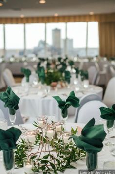 the tables are set up with white linens and greenery