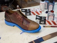 a pair of brown shoes sitting on top of a table next to scissors and glue