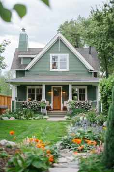 a green house with flowers in the front yard