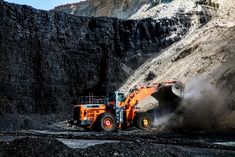 an orange and black bulldozer digging dirt in the mountains