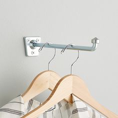 a pair of clothes hanging on a wooden hanger next to a white wall with a striped pillow