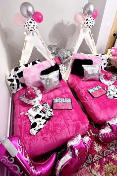 two pink beds with black and white bedding, balloons and decorations on the headboard