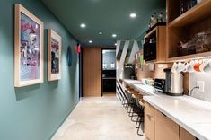 a kitchen with blue walls and white counter tops next to a long wall mounted coffee maker