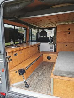 the interior of an rv with wood paneling and storage compartments, including a bed