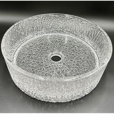 a clear glass bowl with an intricate design on the rim and bottom, sitting on a black surface