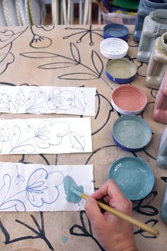 someone is painting flowers on paper with watercolors