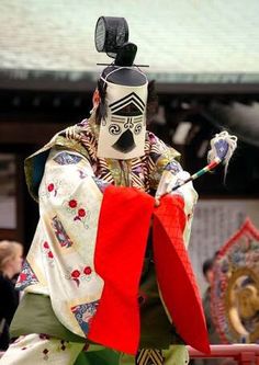 a man dressed in traditional japanese costume holding a red flag and looking at the camera