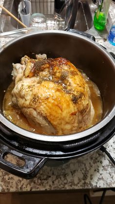 a close up of a chicken in a pot on a stove top with broth