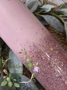 a close up of a pink glittered tube with flowers on the top and leaves around it