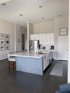 a large kitchen with an island in the middle and pictures on the wall above it