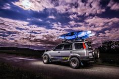 an suv with a surfboard on top parked in the road