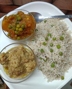 a white plate topped with rice, peas and meat next to two bowls filled with different types of food