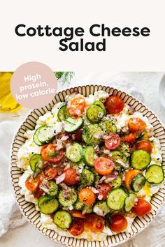 a bowl filled with cucumbers, tomatoes and other vegetables on top of a white table