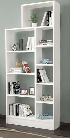 a white book shelf with books and toys on it in front of a gray wall