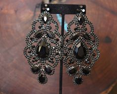 "Oversized statement earrings. These fun and stylish chandelier earrings, in black rhinestones, make a great statement piece for on stage or photos! Size of earrings: 2.25\" Wide and 4.5\" Long. Color: Black Base Metal: silver More colors available! Just message us! Style: Pierced and clip on available Looking for a matching bracelet? https://www.etsy.com/listing/556673735/crystal-wide-bracelet-royal-blue?ref=shop_home_active_9 Looking for the perfect pair of earrings for a special occasion. We Glamorous Black Crystal Earrings With Rhinestones, Glamorous Black Crystal Rhinestone Earrings, Glamorous Black Crystal Earrings, Black Rhinestone Crystal Earrings For Evening, Glamorous Black Crystal Earrings For Wedding, Black And Silver Earrings, Black Statement Earrings, Black Crystal Earrings, Pageant Earrings