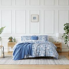 a bedroom with white walls and blue bedding in the center, along with potted plants