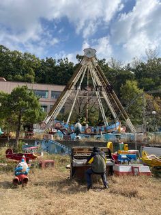 a man sitting on top of a bench next to a carnival ride