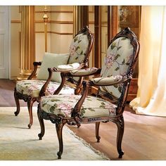 two chairs with floral upholstered back and arms in front of a mirror on the wall