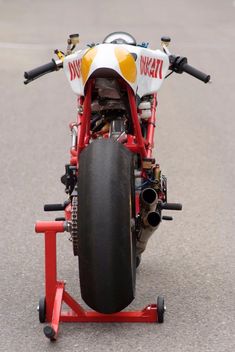 a red motorcycle is parked on the street with its front wheel still attached to it's stand