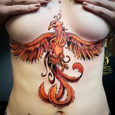 a woman's stomach with an orange bird tattoo on the side, and her hands behind her back