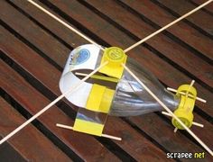 a plastic bottle sitting on top of a wooden table next to two yellow and white sticks