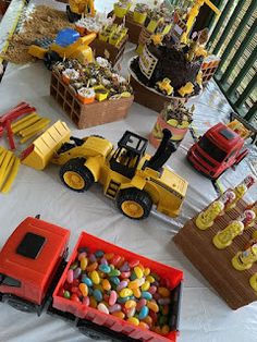 a table topped with lots of candy and construction themed candies on top of a white table cloth