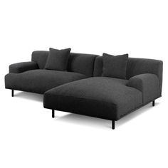 a black couch with pillows on it and one arm extended to the side, sitting in front of a white background