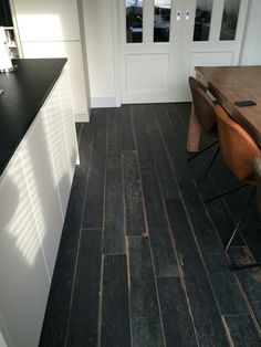 a kitchen with black wood floors and white cabinets