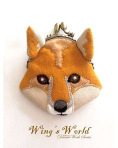 a close up of a key chain with a fox on it's face and the words wing's world written in gold