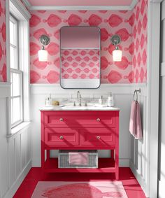 a bathroom with pink and white wallpaper on the walls, red vanity sink and mirror