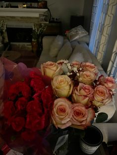 a bouquet of roses sitting on top of a table in front of a couch and window