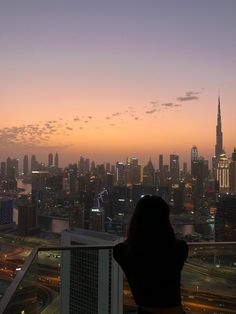 a woman standing on top of a tall building looking out at the cityscape