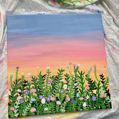 an oil painting of flowers and plants on a canvas with paintbrushes in the background