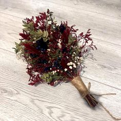 a bouquet of red and white flowers sitting on top of a wooden table with twine