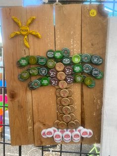 a tree made out of beer bottle caps on a wooden board with other items around it