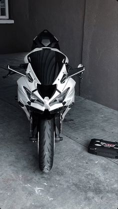 a white motorcycle parked in a garage next to a black and white bag on the ground