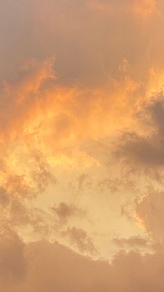 an airplane is flying in the sky at sunset or dawn with orange clouds above it