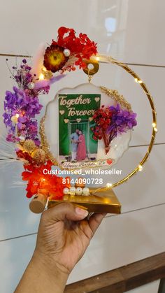 a person holding up an award in front of a white wall with flowers on it